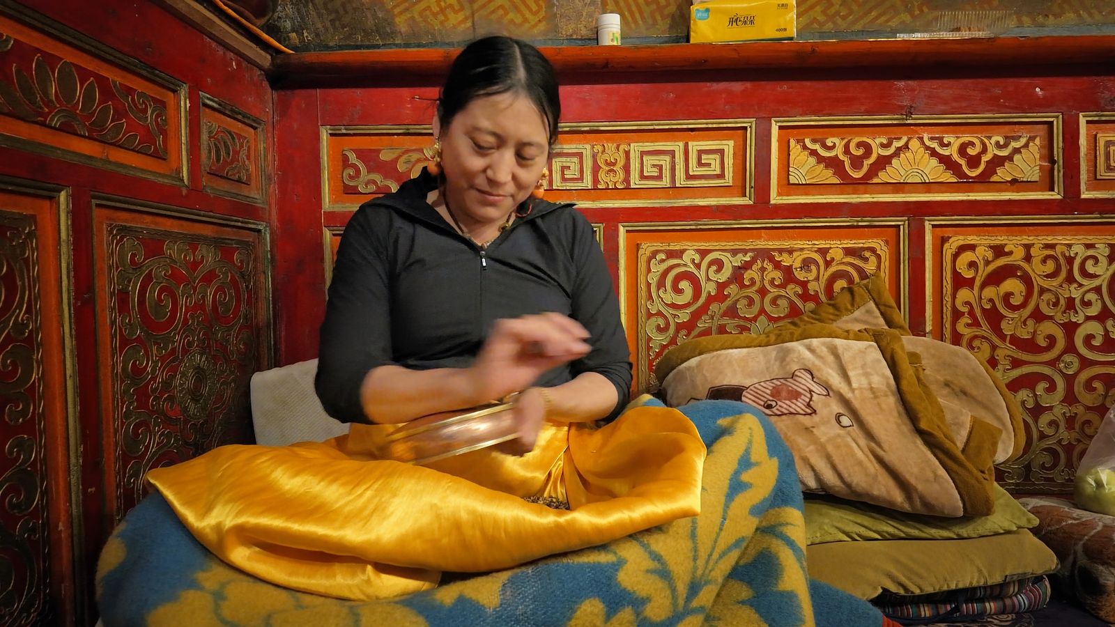 A woman making a mandala offering inside Tagong Monastery